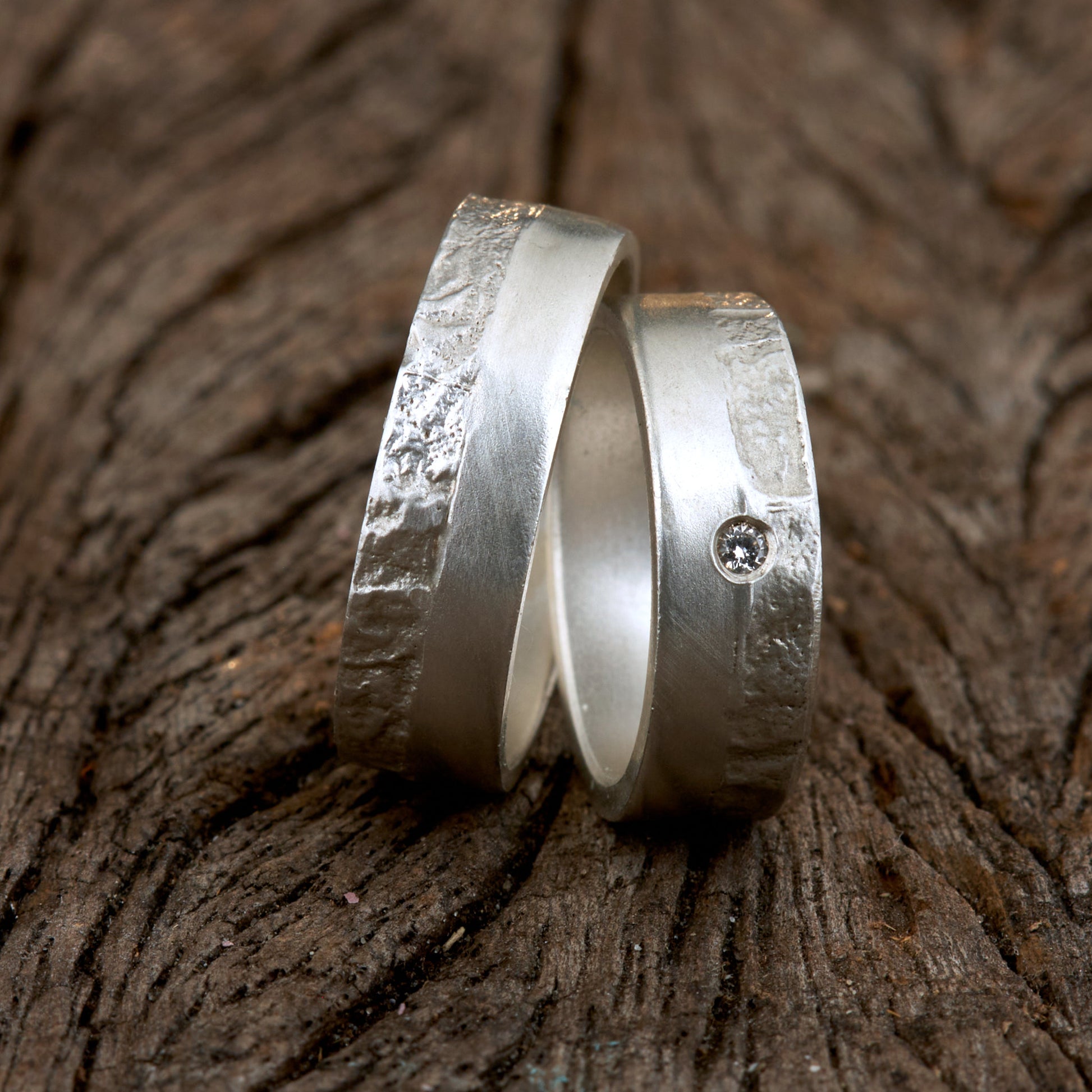 Massive Trauringe aus 925 Silber handgefertigt. Eheringe mit markanter Schieferstruktur retikuliert im Kontrast zu mattierten Oberflächen. Damenring ca. 6mm breit mit einem bündig gefassten 2mm Brillanten (TW/si). Herrenring ca. 6mm breit, massiv und charakterstark. Einzigartiges Partnerring-Set mit organischer Textur, inspiriert von natürlichem Fels. Handgemacht in eigener Werkstatt in Deutschland, keine CNC-Massenware. Hochwertige Unikate für Individualisten