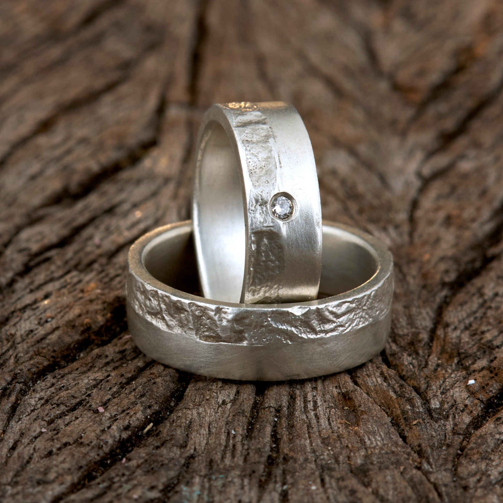 Massive Trauringe aus 925 Silber handgefertigt. Eheringe mit markanter Schieferstruktur retikuliert im Kontrast zu mattierten Oberflächen. Damenring ca. 6mm breit mit einem bündig gefassten 2mm Brillanten (TW/si). Herrenring ca. 6mm breit, massiv und charakterstark. Einzigartiges Partnerring-Set mit organischer Textur, inspiriert von natürlichem Fels. Handgemacht in eigener Werkstatt in Deutschland, keine CNC-Massenware. Hochwertige Unikate für Individualisten