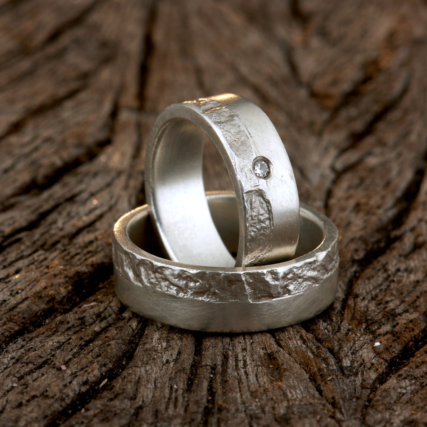 Massive Trauringe aus 925 Silber handgefertigt. Eheringe mit markanter Schieferstruktur retikuliert im Kontrast zu mattierten Oberflächen. Damenring ca. 6mm breit mit einem bündig gefassten 2mm Brillanten (TW/si). Herrenring ca. 6mm breit, massiv und charakterstark. Einzigartiges Partnerring-Set mit organischer Textur, inspiriert von natürlichem Fels. Handgemacht in eigener Werkstatt in Deutschland, keine CNC-Massenware. Hochwertige Unikate für Individualisten