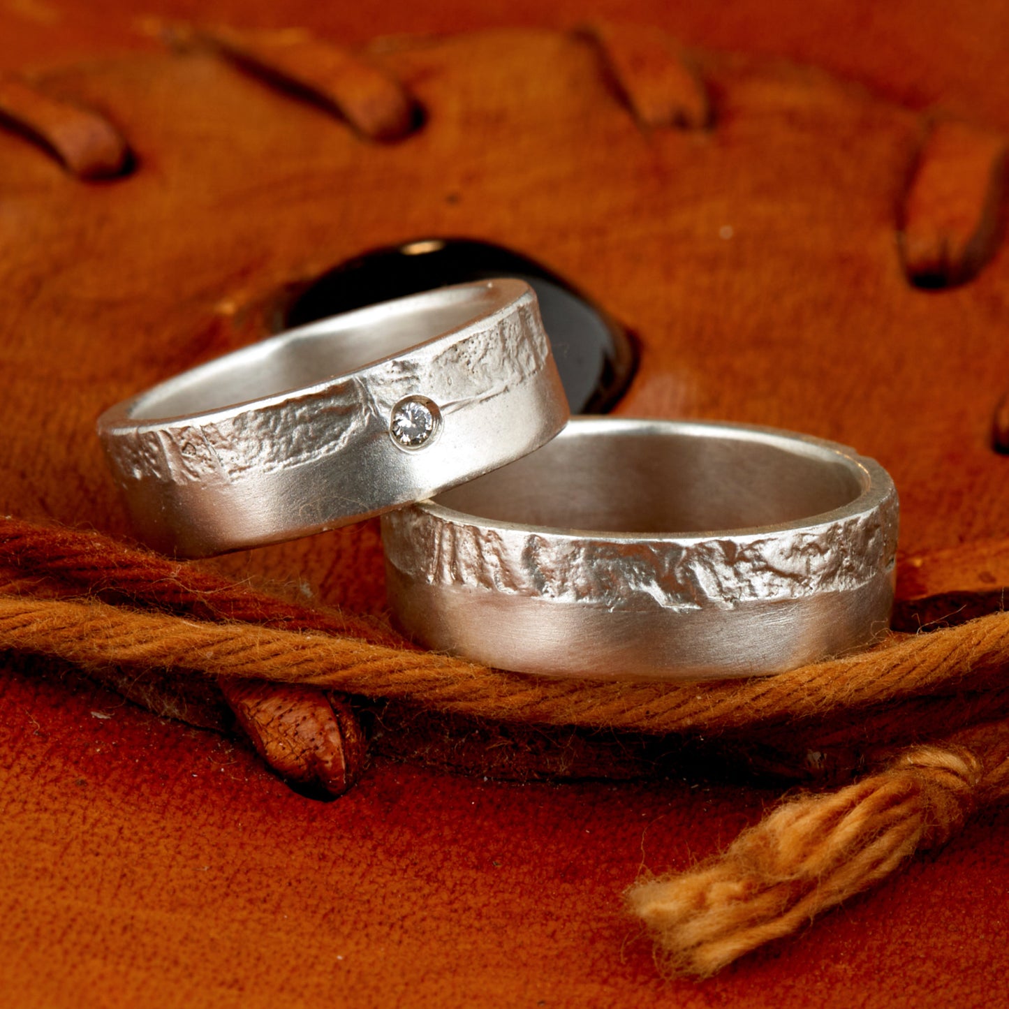 Massive Trauringe aus 925 Silber handgefertigt. Eheringe mit markanter Schieferstruktur retikuliert im Kontrast zu mattierten Oberflächen. Damenring ca. 6mm breit mit einem bündig gefassten 2mm Brillanten (TW/si). Herrenring ca. 6mm breit, massiv und charakterstark. Einzigartiges Partnerring-Set mit organischer Textur, inspiriert von natürlichem Fels. Handgemacht in eigener Werkstatt in Deutschland, keine CNC-Massenware. Hochwertige Unikate für Individualisten