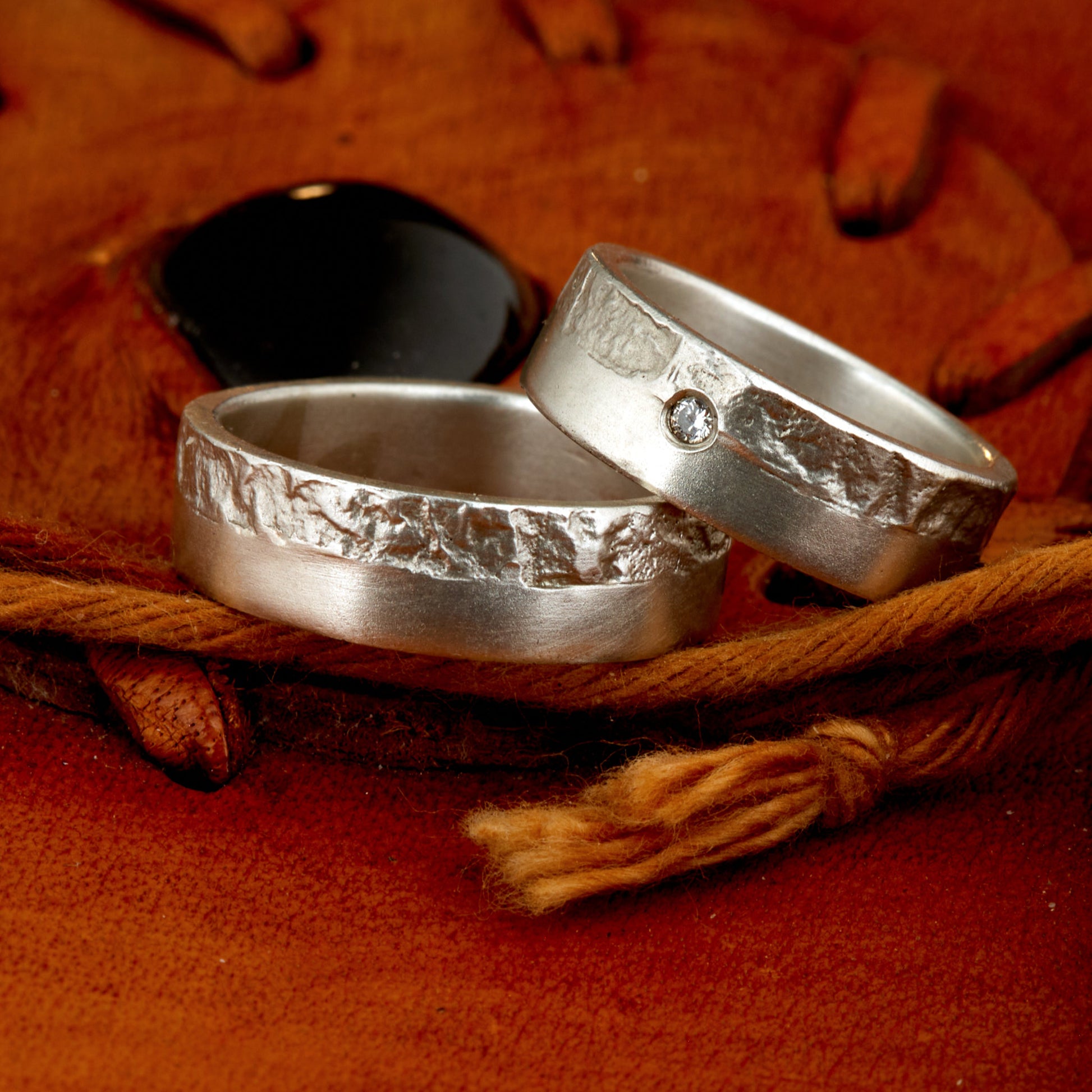 Massive Trauringe aus 925 Silber handgefertigt. Eheringe mit markanter Schieferstruktur retikuliert im Kontrast zu mattierten Oberflächen. Damenring ca. 6mm breit mit einem bündig gefassten 2mm Brillanten (TW/si). Herrenring ca. 6mm breit, massiv und charakterstark. Einzigartiges Partnerring-Set mit organischer Textur, inspiriert von natürlichem Fels. Handgemacht in eigener Werkstatt in Deutschland, keine CNC-Massenware. Hochwertige Unikate für Individualisten