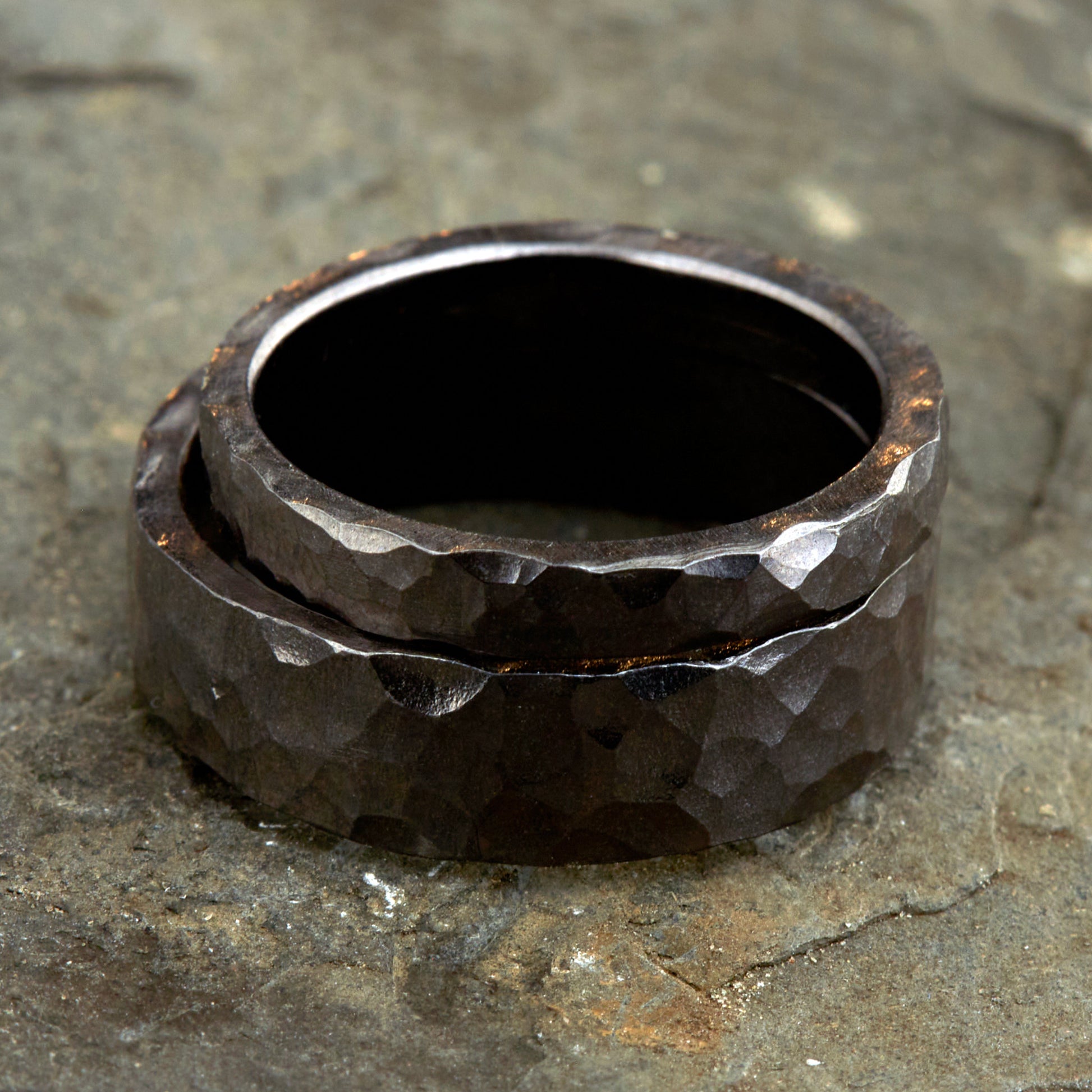 
Handgefertigtes Ehering-Set aus massivem Tantal auf rustikalem Leder. Herrenring (6mm) und Damenring (4mm) mit markanter, gehämmerter Oberfläche in dunklem Anthrazit. Einzigartige Schmiedekunst für exklusive Hochzeitsringe. SEO-Keywords: Tantal Eheringe gehämmert, dunkle Trauringe, Tantalum Wedding Bands, nachhaltiger Luxusschmuck, seltene Edelmetalle Hochzeit. Sichtbare Details der individuellen Textur und des tiefen, metallischen Glanzes.