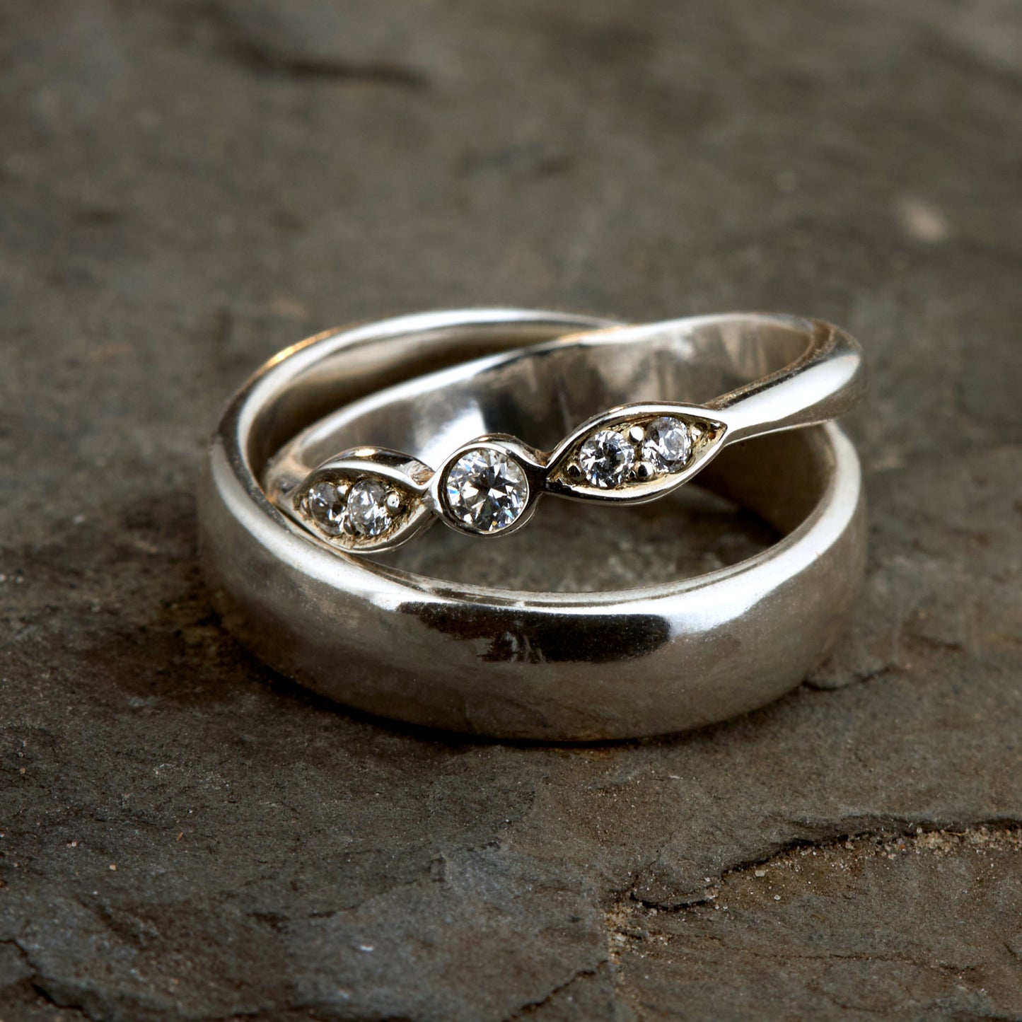 Exklusives Ehering-Set aus 925 Silber auf braunem Leder. Damenring (4mm) mit 5 handgefassten Moissaniten (1x 3mm, 4x 2mm) für maximale Lichtreflexion. Massiver Herrenring (6mm breit, 2mm stark) in Hochglanz-Optik. Nachhaltige Trauringe als ethische Alternative zum Diamanten. SEO-Keywords: Moissanit Trauringe Silber, handgefertigte Hochzeitsringe Set, nachhaltiger Schmuck, 925 Silber Ringe mit Moissanit, Eheringe Set günstig Luxus.