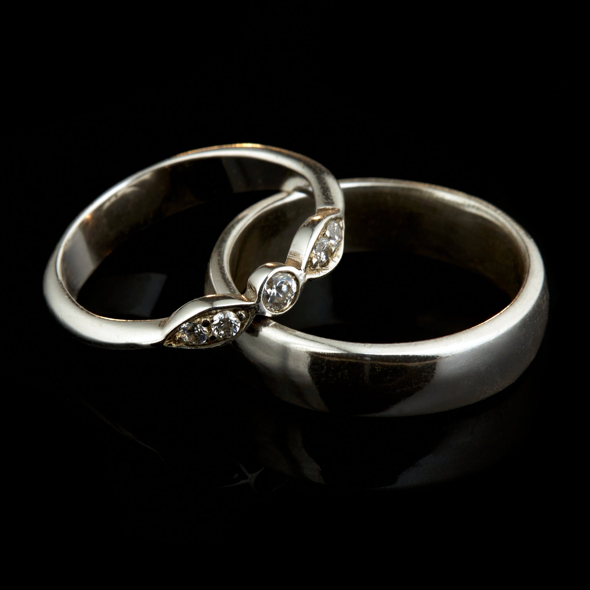 Exklusives Ehering-Set aus 925 Silber auf braunem Leder. Damenring (4mm) mit 5 handgefassten Moissaniten (1x 3mm, 4x 2mm) für maximale Lichtreflexion. Massiver Herrenring (6mm breit, 2mm stark) in Hochglanz-Optik. Nachhaltige Trauringe als ethische Alternative zum Diamanten. SEO-Keywords: Moissanit Trauringe Silber, handgefertigte Hochzeitsringe Set, nachhaltiger Schmuck, 925 Silber Ringe mit Moissanit, Eheringe Set günstig Luxus.