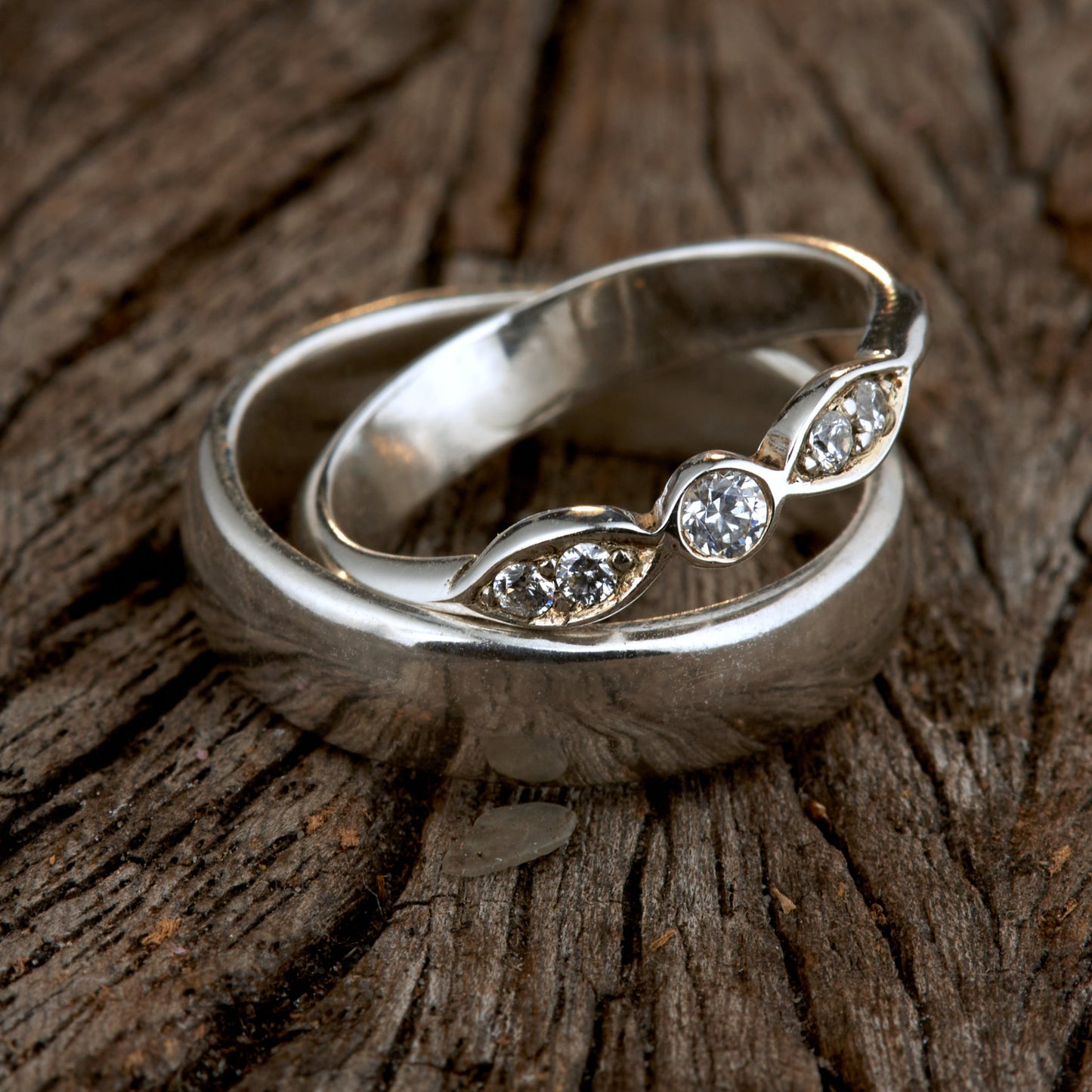 Exklusives Ehering-Set aus 925 Silber auf braunem Leder. Damenring (4mm) mit 5 handgefassten Moissaniten (1x 3mm, 4x 2mm) für maximale Lichtreflexion. Massiver Herrenring (6mm breit, 2mm stark) in Hochglanz-Optik. Nachhaltige Trauringe als ethische Alternative zum Diamanten. SEO-Keywords: Moissanit Trauringe Silber, handgefertigte Hochzeitsringe Set, nachhaltiger Schmuck, 925 Silber Ringe mit Moissanit, Eheringe Set günstig Luxus.