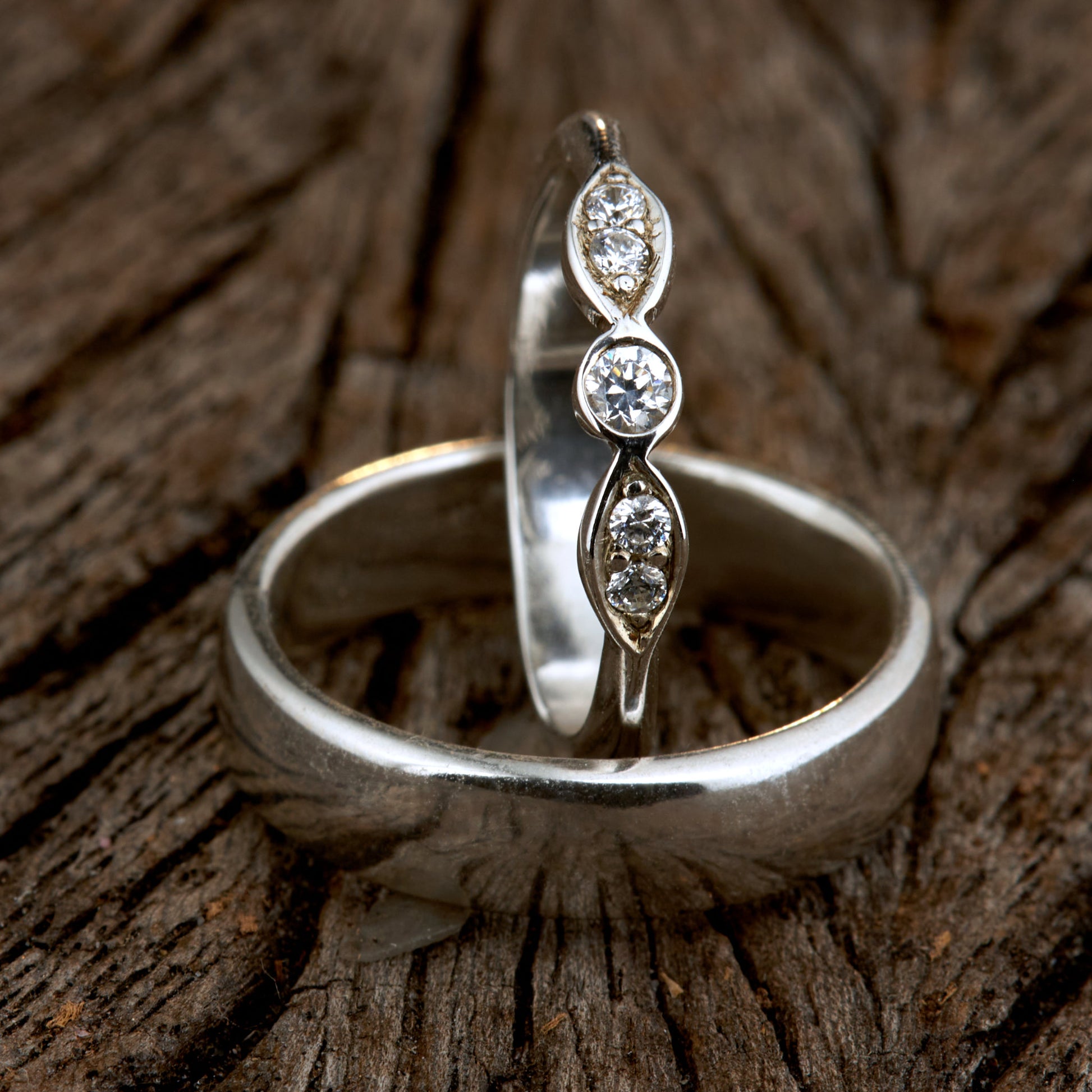 Exklusives Ehering-Set aus 925 Silber auf braunem Leder. Damenring (4mm) mit 5 handgefassten Moissaniten (1x 3mm, 4x 2mm) für maximale Lichtreflexion. Massiver Herrenring (6mm breit, 2mm stark) in Hochglanz-Optik. Nachhaltige Trauringe als ethische Alternative zum Diamanten. SEO-Keywords: Moissanit Trauringe Silber, handgefertigte Hochzeitsringe Set, nachhaltiger Schmuck, 925 Silber Ringe mit Moissanit, Eheringe Set günstig Luxus.