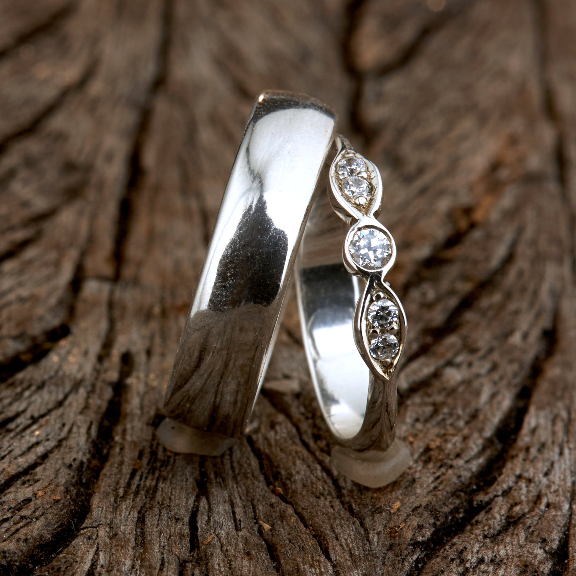 Exklusives Ehering-Set aus 925 Silber auf braunem Leder. Damenring (4mm) mit 5 handgefassten Moissaniten (1x 3mm, 4x 2mm) für maximale Lichtreflexion. Massiver Herrenring (6mm breit, 2mm stark) in Hochglanz-Optik. Nachhaltige Trauringe als ethische Alternative zum Diamanten. SEO-Keywords: Moissanit Trauringe Silber, handgefertigte Hochzeitsringe Set, nachhaltiger Schmuck, 925 Silber Ringe mit Moissanit, Eheringe Set günstig Luxus.