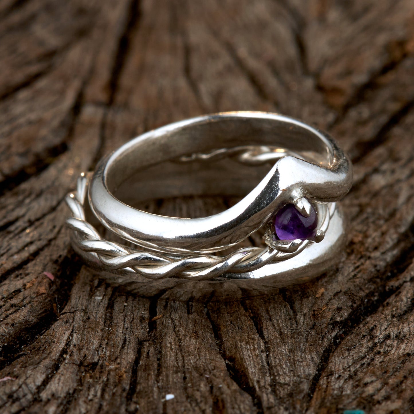 Handgefertigtes Ehering-Set aus 925 Silber auf Leder. 3-teiliges Damen-Set bestehend aus einem 3mm Wishbone-Ring mit Amethyst und einem 2mm Kordelring. Daneben ein massiver 4mm Herrenring im Halbrund-Profil. Zeitloses Design mit lila Edelstein für die Hochzeit. SEO-Keywords: Wishbone Eheringe Silber, Amethyst Trauringe Set, handgefertigte Silberringe, 925 Sterlingsilber Schmuck, Kordelring Hochzeit. Sichtbare Details der hochwertigen Handarbeit und Steinbesetzung.